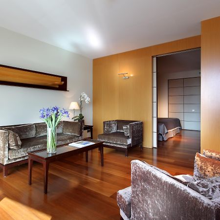 ยูโรสตาร์ แกรนด์ มารีน่า จีเอล โฮเต็ล Hotel บาร์เซโลนา ภายนอก รูปภาพ The photo shows a modern living room with a warm and inviting atmosphere. It features two armchairs and a sofa, all in a plush, dark fabric. A coffee table sits in the center, with a vase of fresh flowers adding a pop of color. The room has hardwood 