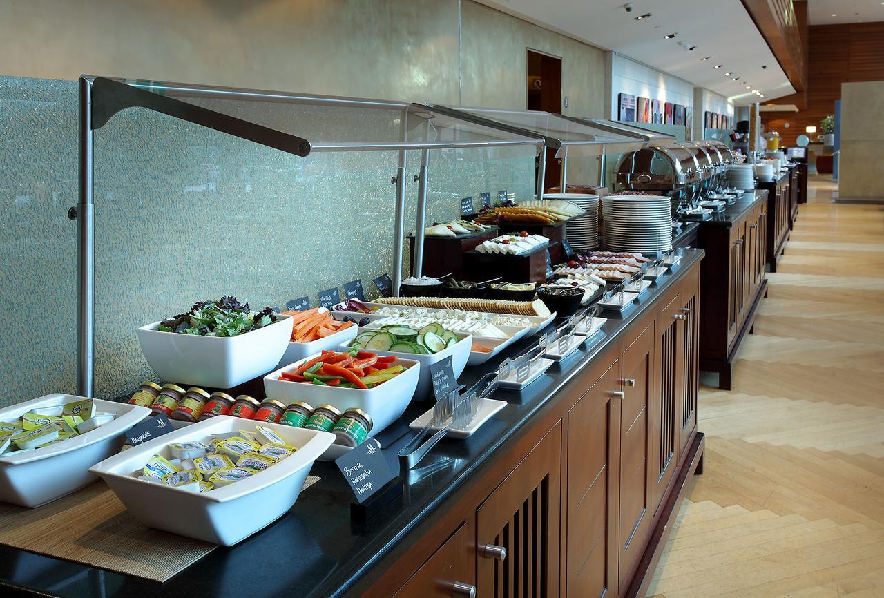 ยูโรสตาร์ แกรนด์ มารีน่า จีเอล โฮเต็ล Hotel บาร์เซโลนา ภายนอก รูปภาพ The photo shows a buffet spread featuring a variety of dishes arranged along a long serving counter. There are several bowls and platters containing fresh salads, sliced vegetables, and other food items. The setting appears modern and well-organized,