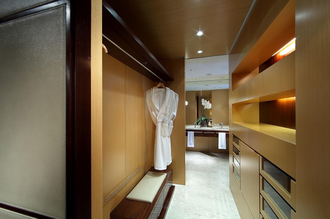 ยูโรสตาร์ แกรนด์ มารีน่า จีเอล โฮเต็ล Hotel บาร์เซโลนา ภายนอก รูปภาพ The photo depicts a stylish interior space, likely a dressing area or walk-in closet. The walls are finished in warm wood tones, creating a modern and elegant atmosphere. A white robe hangs on a sleek hook, and there is a bench next to it. The area i